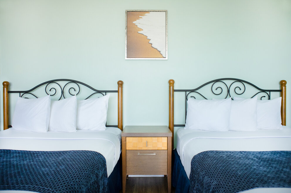 two beds with white pillows and blue blankets