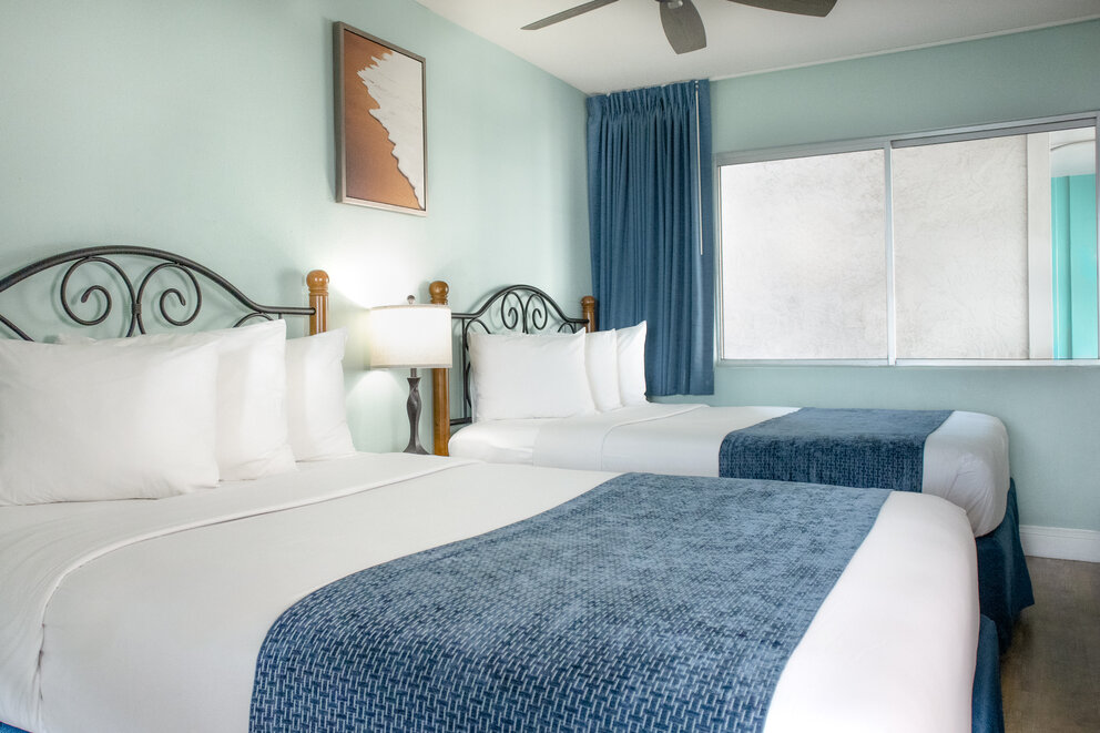 a room with two beds and a fan