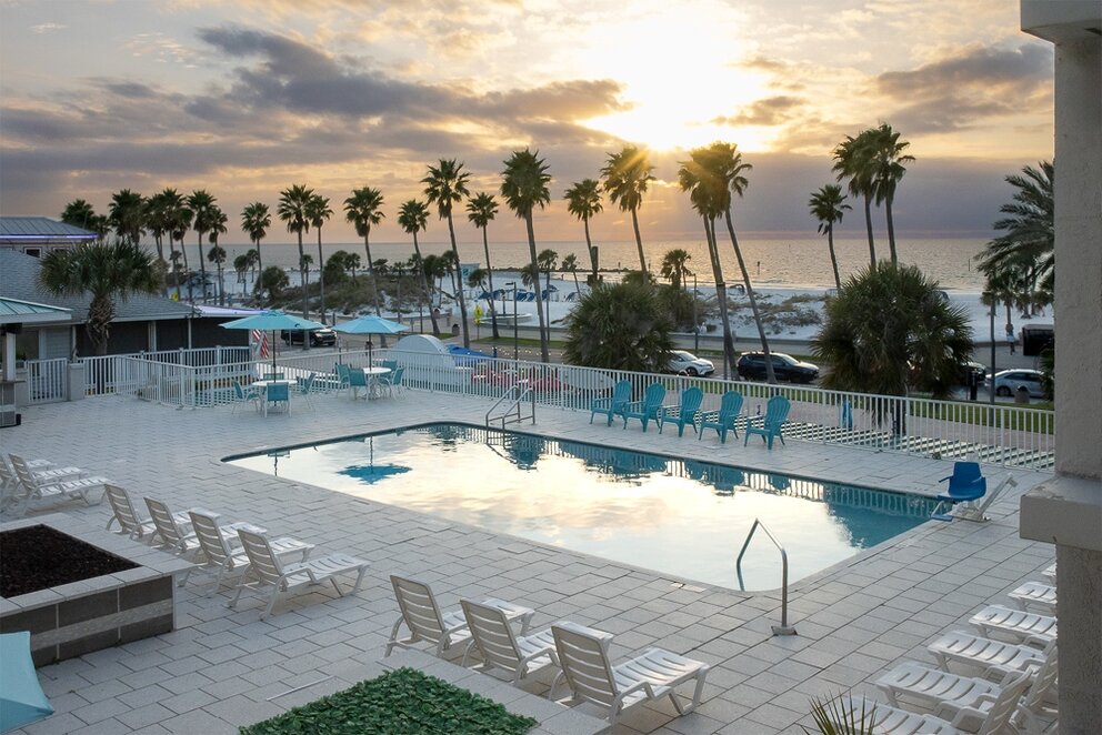a pool with chairs and a beach in the background