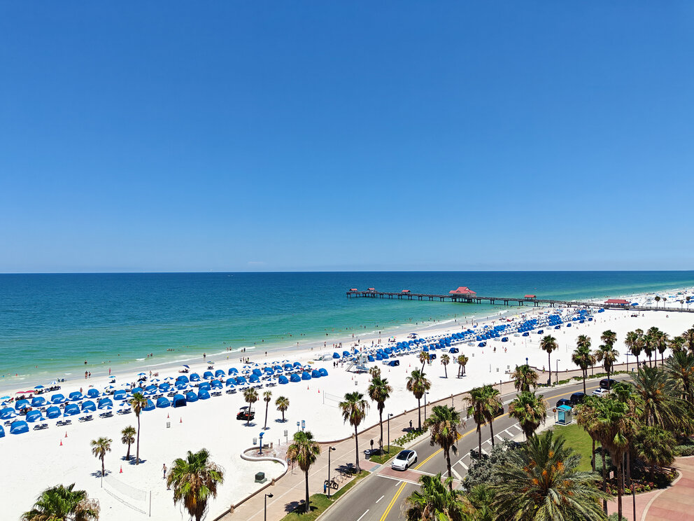 a beach with palm trees and blue umbrellas