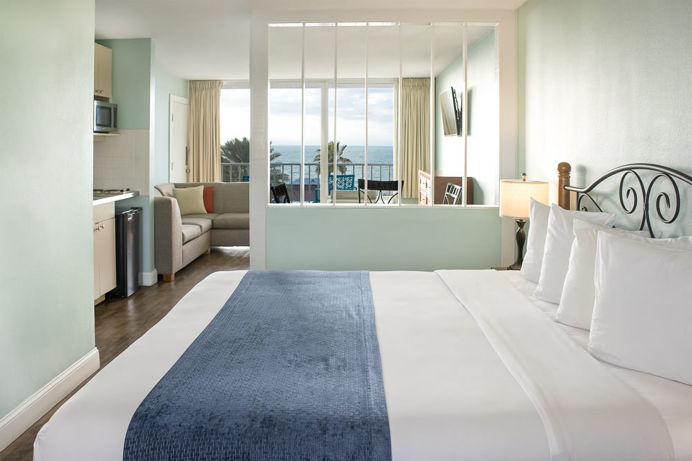 a room with a bed and a view of the ocean